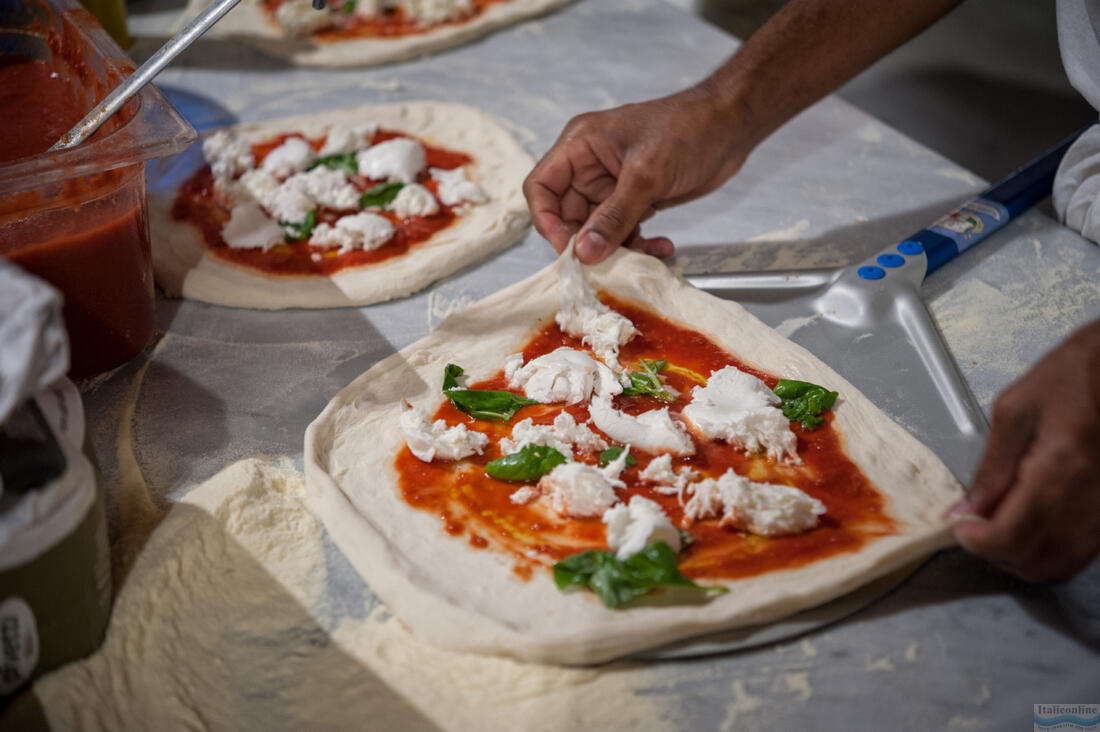 Pizzaiolo klade pizzové těsto na pizza lopatu